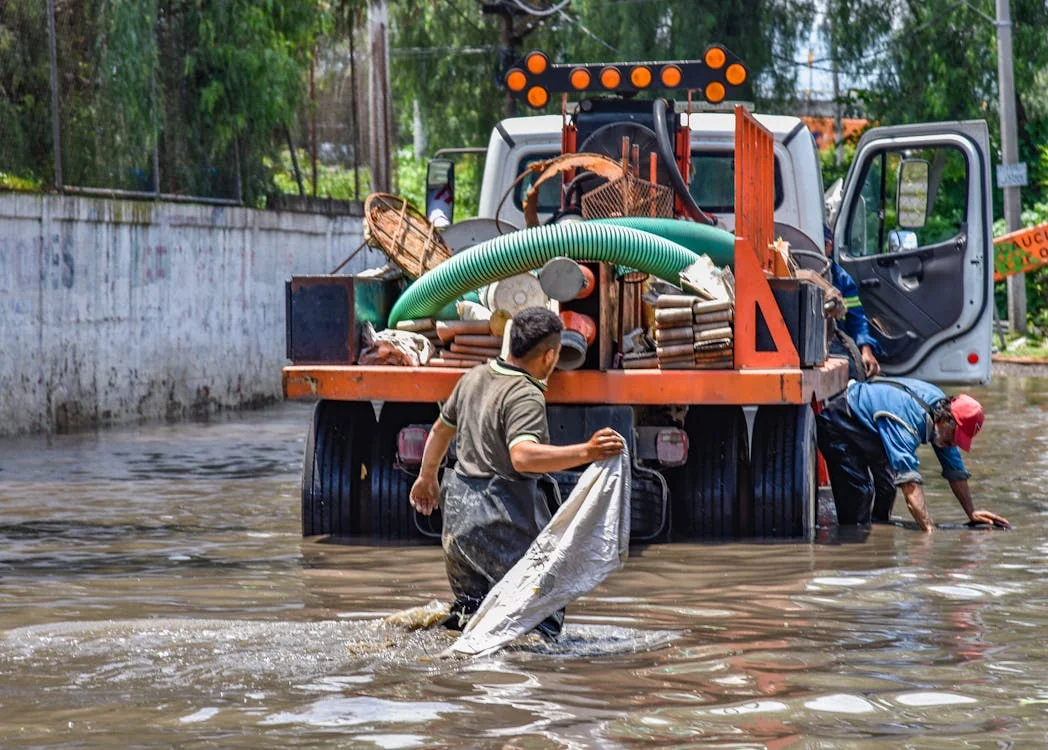 water damage restoration dayton ohio — technician extracting floodwater from flooded street